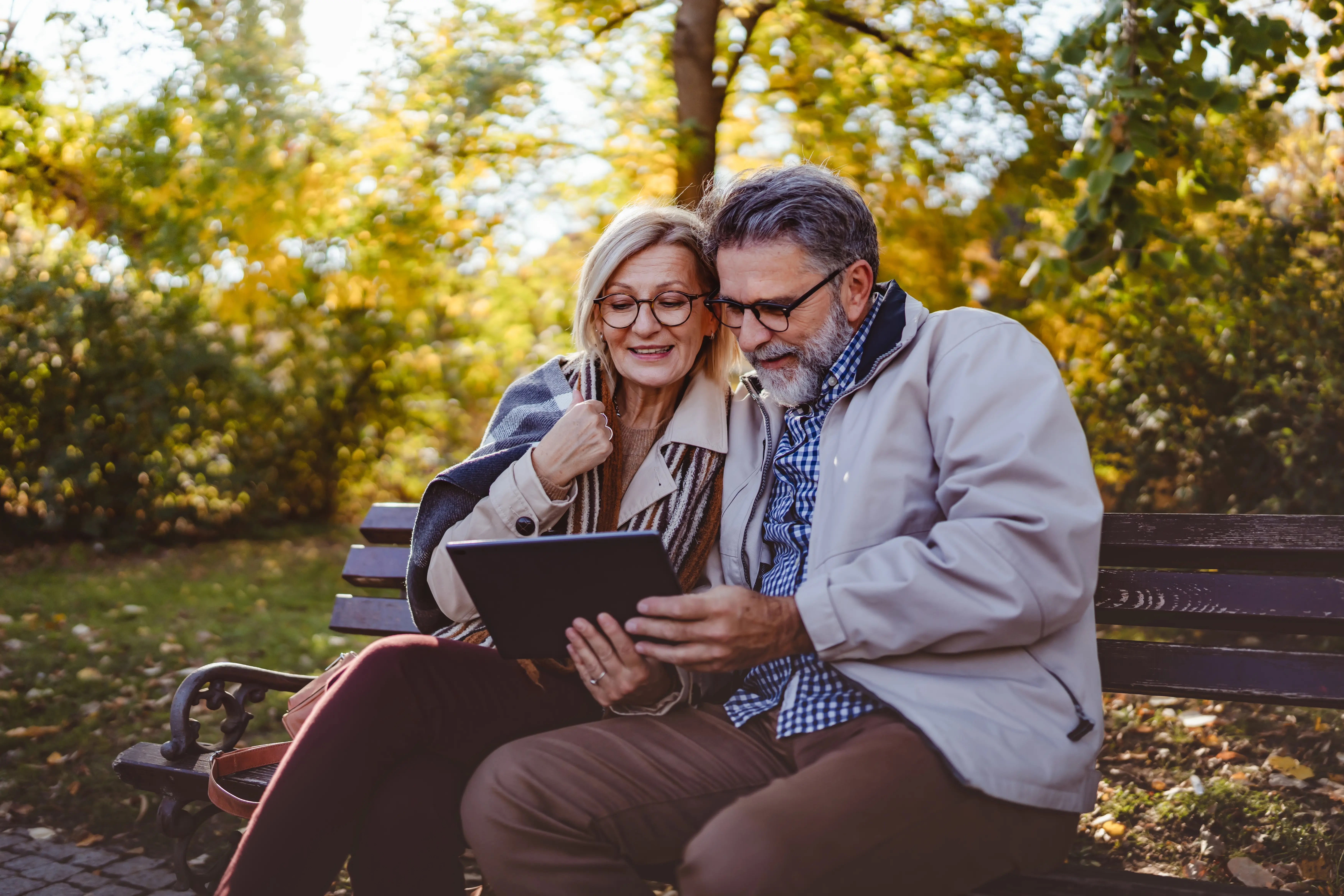couple de personnes senior heureux assis sur un banc en automne
